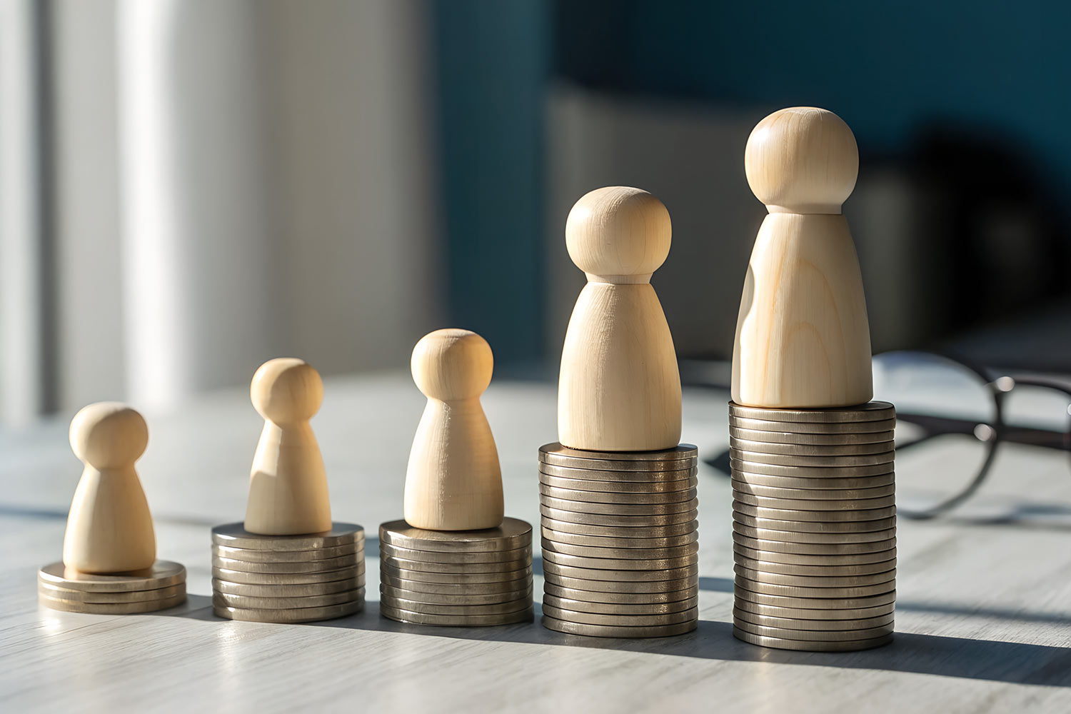 stacks of coins lined up in ascending order with wooden blocks representing family members on top of each coin