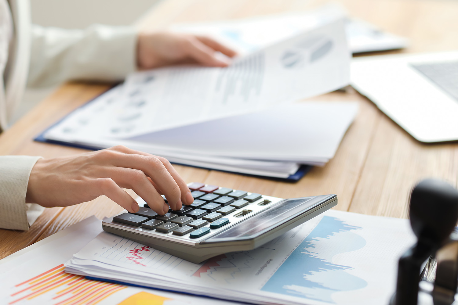 woman using a calculator on the desk while also holding a piece of paper